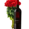 A bottle of red wine beside a vibrant bouquet of red roses, creating a romantic and elegant setting.