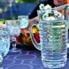 A pitcher of water beside a glass of wine elegantly placed on a wooden table.