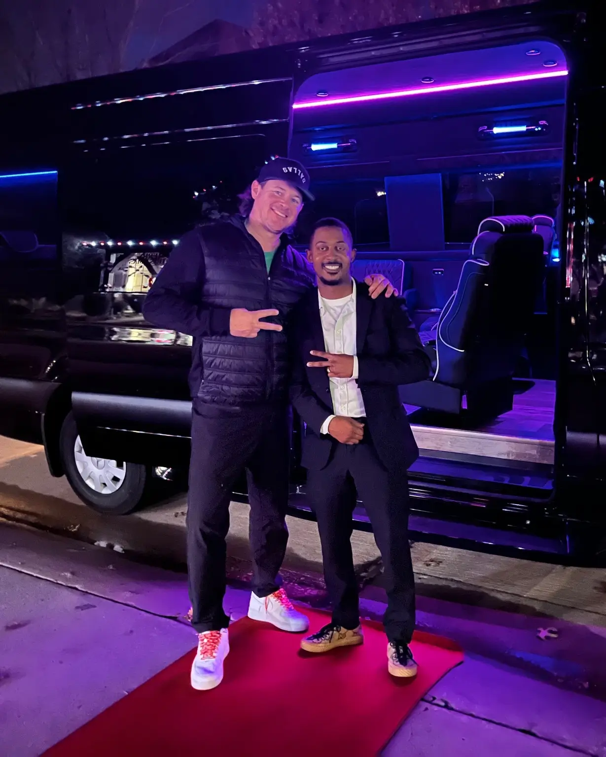 Two men in suits standing beside a sleek black limousine, exuding professionalism and elegance.