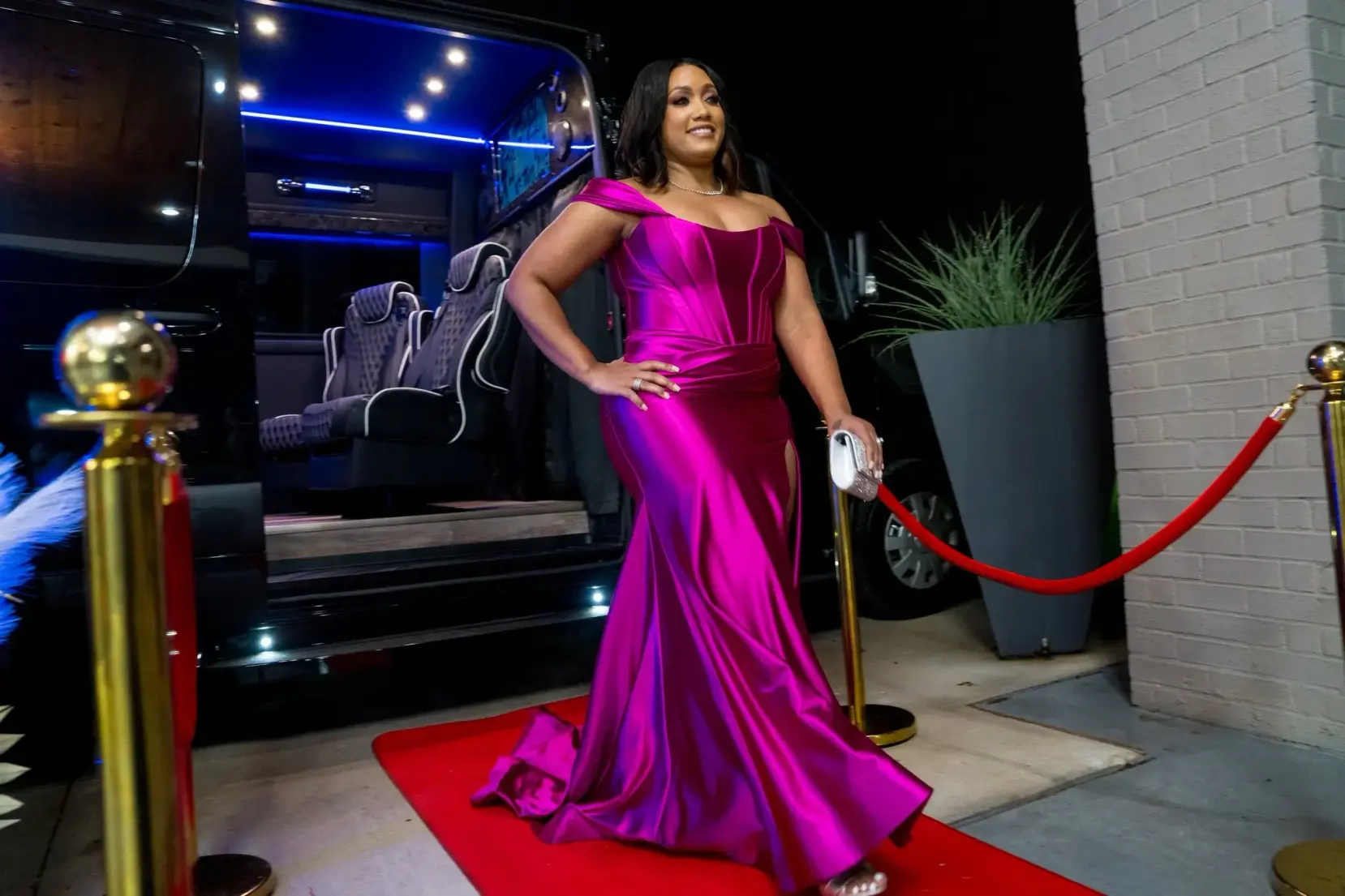 A woman in a purple dress poses confidently on a vibrant red carpet.