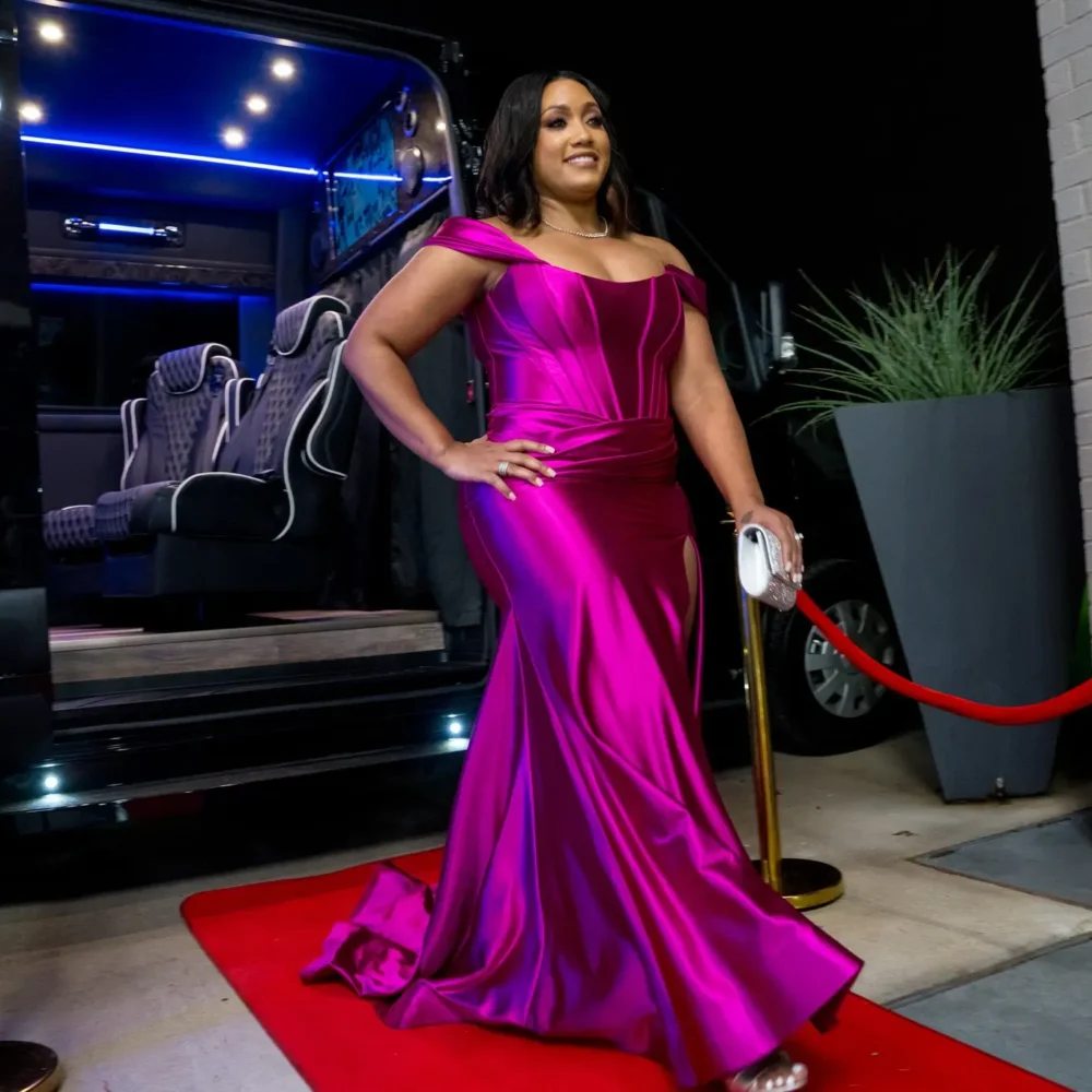 A woman in a purple dress poses confidently on a vibrant red carpet, showcasing elegance and style.