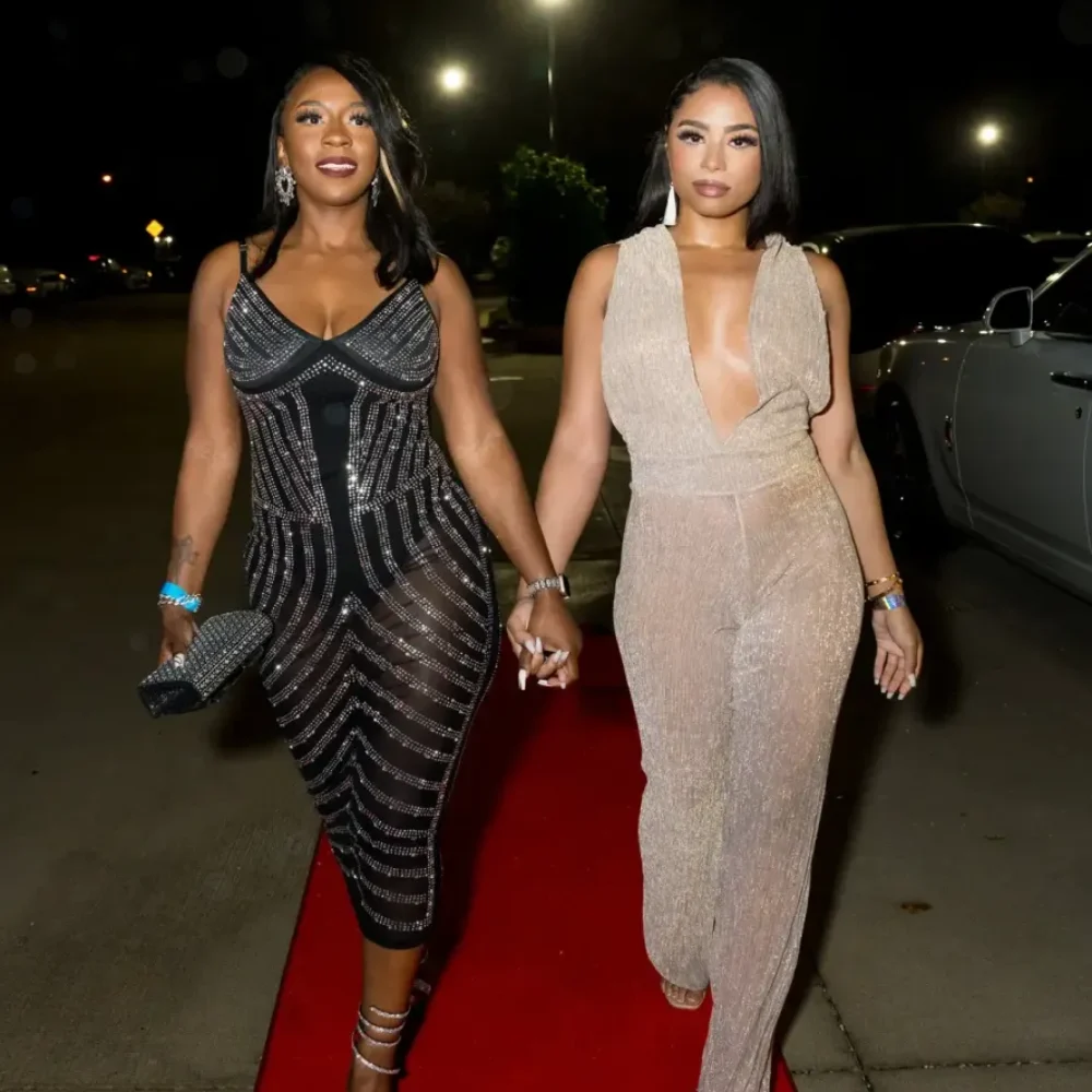 Two women in identical outfits confidently walking together on a vibrant red carpet.